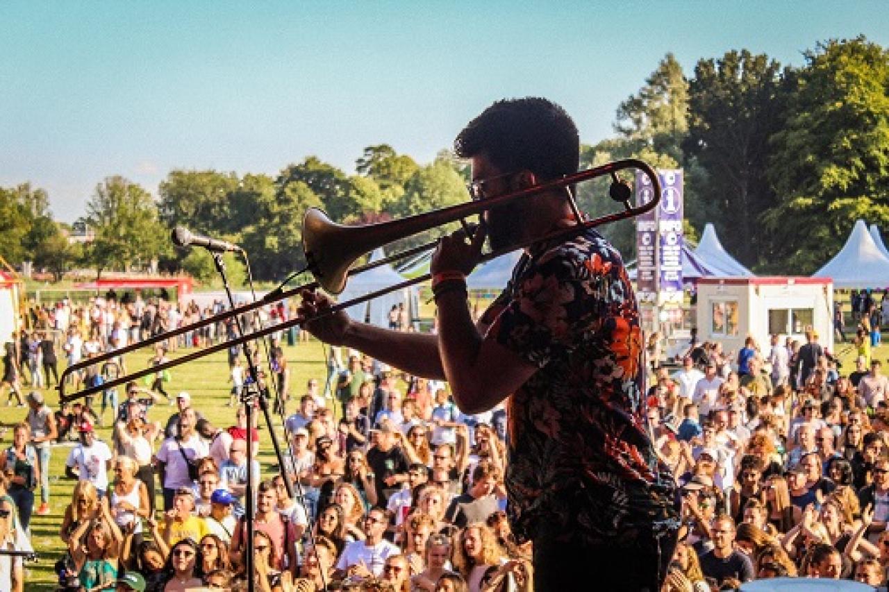 Deelnemer speelt trombone op podium van het Haags Veld op Parkpop. Fotografie: Nadege Dosso